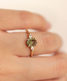 a woman's hand with a ring on it and a green stone in the middle