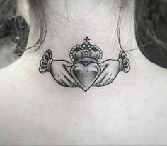 a woman's back neck with a crown and two hands holding a heart