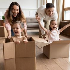 a family is playing with cardboard boxes on the floor