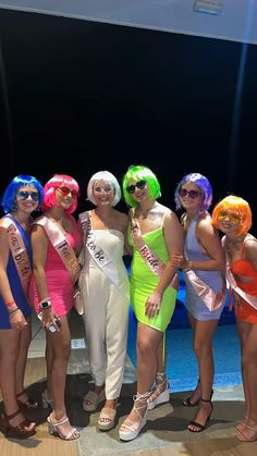 four women dressed in colorful wigs posing for a photo with one woman wearing an orange and white dress