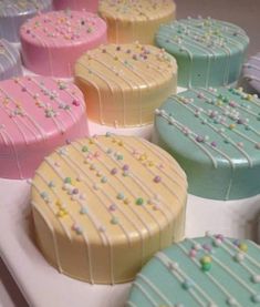 there are many different colored cakes on the trays that have frosted icing and sprinkles