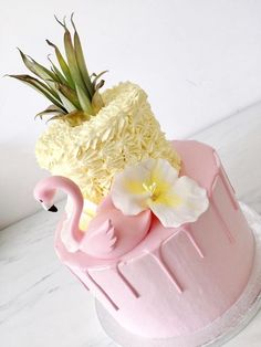 a pink cake with white flowers and a flamingo decoration on the top is sitting on a marble table