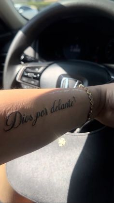 a person driving a car with a tattoo on their arm that says dios por diante