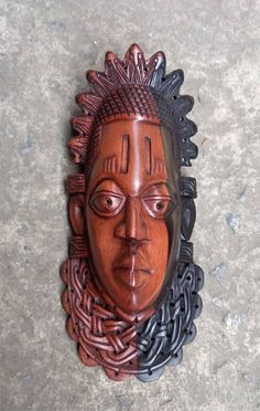 a wooden mask with braids on it's head sitting on the cement floor