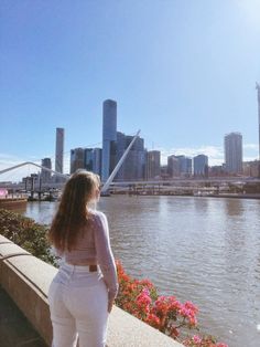 a woman in white pants looking at the water