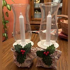 two glass candlesticks sitting on top of a wooden table