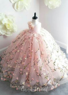 a dress made out of tulle with pink flowers on the top and bottom, sitting in front of a white wall