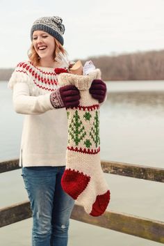 a woman holding a christmas stocking by the water