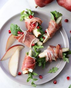 apples and prosciutto wrapped in bacon on a white plate with pomegranates