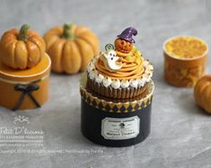 cupcakes with frosting and decorations sitting on a table next to small pumpkins