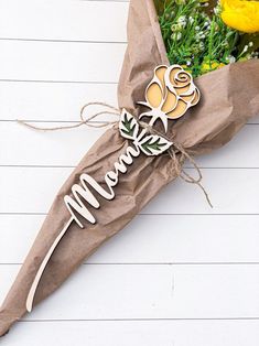 a bouquet of flowers wrapped in brown paper with the word mom written on it,