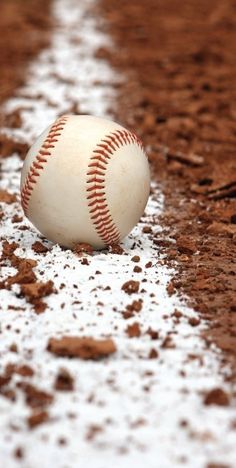 a baseball sitting on top of a field covered in dirt and mud next to home plate