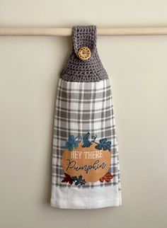 a kitchen towel hanging on the wall with a wooden hanger holding an item that says hey there pumpkin