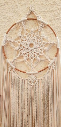 a white dream catcher hanging on the side of a wall