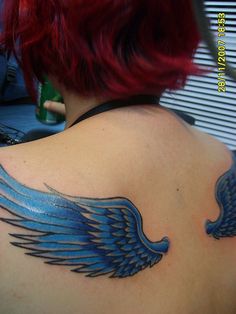 a woman with red hair has a blue wing tattoo on her upper back and shoulder