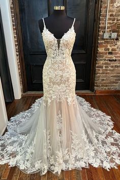 a wedding dress is displayed on a mannequin in front of a brick wall