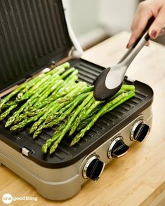 a person is grilling asparagus on a griddle