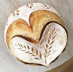 a close up of a loaf of bread with leaves on the side and heart shaped crust