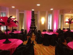 the room is set up with pink and black linens for tables, chairs, and centerpieces