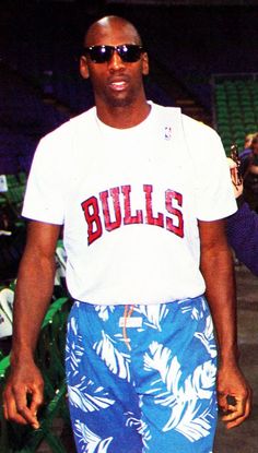 a man in blue and white shorts standing next to a tennis racket