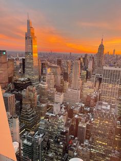 an aerial view of the city at sunset with skyscrapers and water tanks in the foreground