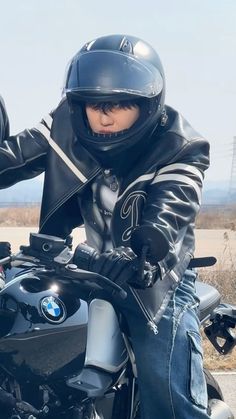 a man riding on the back of a motorcycle wearing a helmet and leather jacket,