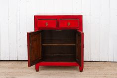 an old red cabinet with two drawers on the bottom and one drawer open to reveal something