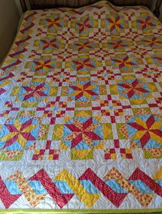 a bed with a quilt on top of it in a room next to a window