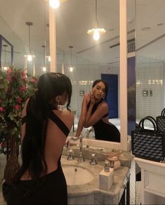 a woman standing in front of a bathroom mirror next to a sink and counter top