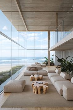 a living room with couches and tables in front of large windows overlooking the beach