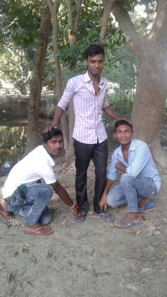 three men are standing in the dirt by some trees