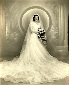 an old black and white photo of a woman in a wedding dress holding a bouquet