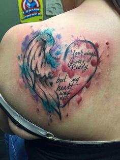 the back of a woman's shoulder with an angel and heart tattoo on it