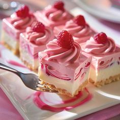 four desserts with raspberries on top are sitting on a square white plate