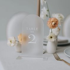 the table number is displayed with white flowers in vases and silverware on the table