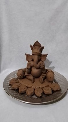 an elephant figurine sitting on top of a pile of leaves and nuts in front of a white background