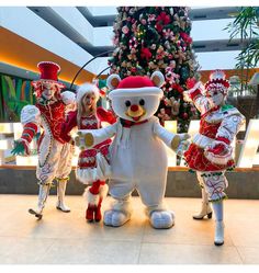 some people are dressed up in costumes and standing next to a christmas tree at the mall