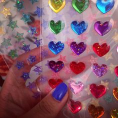 a hand holding a bag filled with lots of different colored hearts and star shaped candies