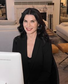 a woman sitting in front of a laptop computer on top of a desk next to a fireplace