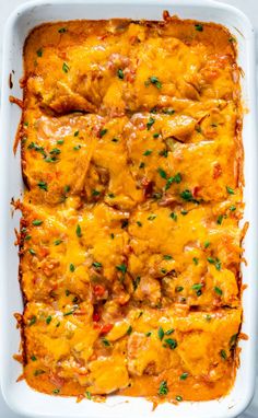 chicken enchilada casserole in a white dish with cheese and parsley