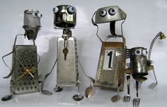 three metal robot sculptures with forks and spoons in front of them, one holding a clock