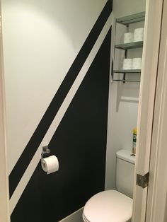 a small bathroom with black and white stripes painted on the wall, toilet paper dispenser next to it