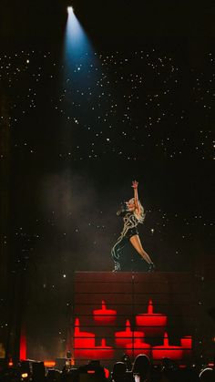 a person standing on top of a stage in the middle of a crowd at a concert