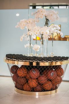 a basket filled with basketballs and flowers on top of a marble floor in front of a wall