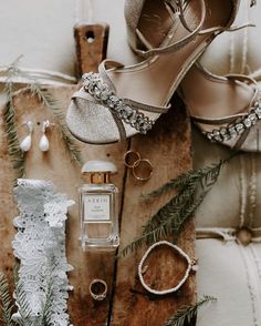 wedding shoes, rings and jewelry are laid out on a piece of wood