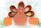 a paper turkey and two pumpkins on a marble surface