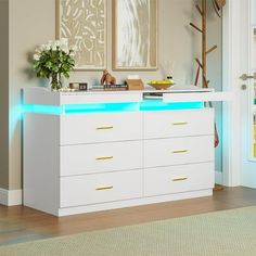 a white dresser with blue lights on the top and drawers below it in a living room