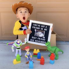 a young boy holding up a sign with toy figures around him