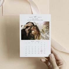 a hand holding a calendar card with a photo on it and a pink ribbon around it