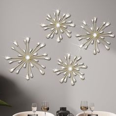 a dining room table and chairs with wine glasses in front of the wall decorated with crystal snowflakes